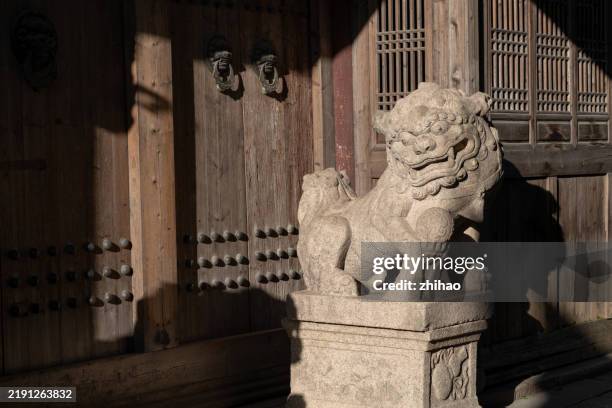a stone lion at the entrance of a traditional chinese building - chinese foo dog stock-fotos und bilder