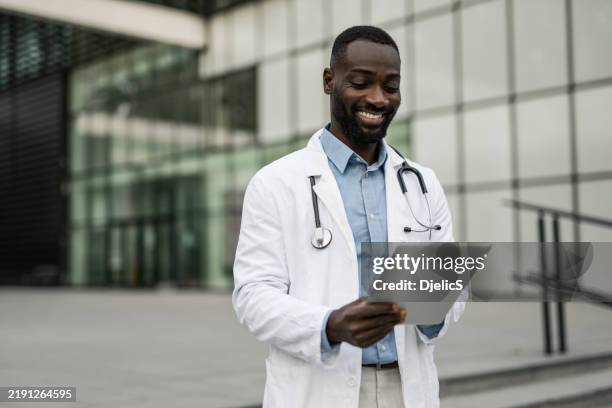 male doctor using digital tablet outdoors - attractive doctor stock pictures, royalty-free photos & images