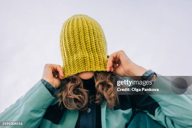 person pulling knitted beanie over face hiding identity - gesicht verstecken stock-fotos und bilder