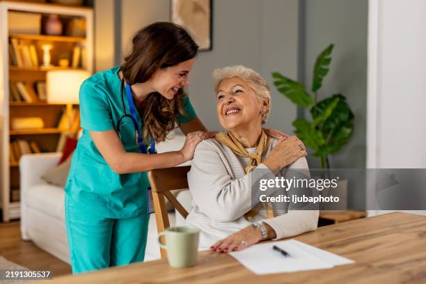 senior woman and nurse smiling in a comfortable and supportive home environment - words of support and encouragement stock pictures, royalty-free photos & images