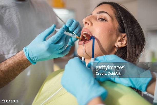 dentist giving a patient a local dental anesthesia using a syringe - implante imagens e fotografias de stock