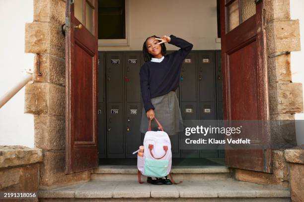 smiling girl making peace sign and holding backpack - kids open backpack stock pictures, royalty-free photos & images