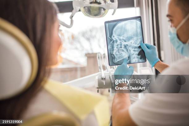 ein zahnarzt zeigt einer patientin in der zahnarztpraxis ein röntgenbild des ober- und unterkiefers - künstliches gebiss stock-fotos und bilder