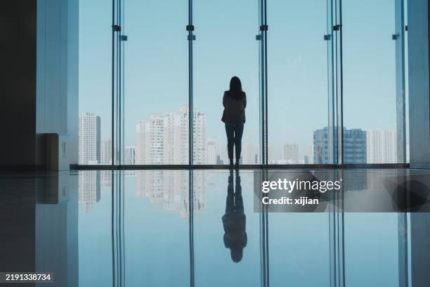 donne d'affari in piedi vicino alla finestra che guarda lo skyline della città - guardare fuori dalla finestra foto e immagini stock