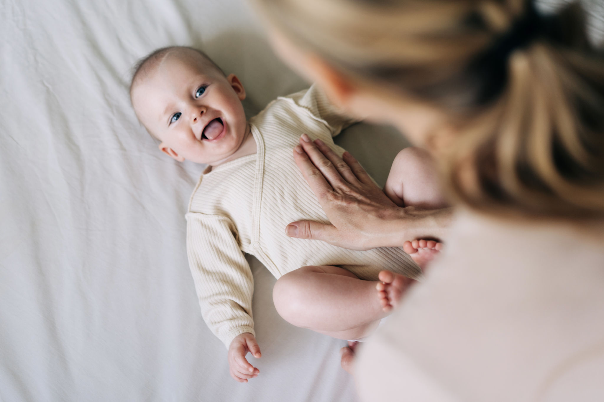 Mom Changes The Bodysuit Of A Cheerful Cute Baby After Changing The Diaper. Mom Changes The Bodysuit Of A Cheerful Cute Baby After Changing The Diaper.