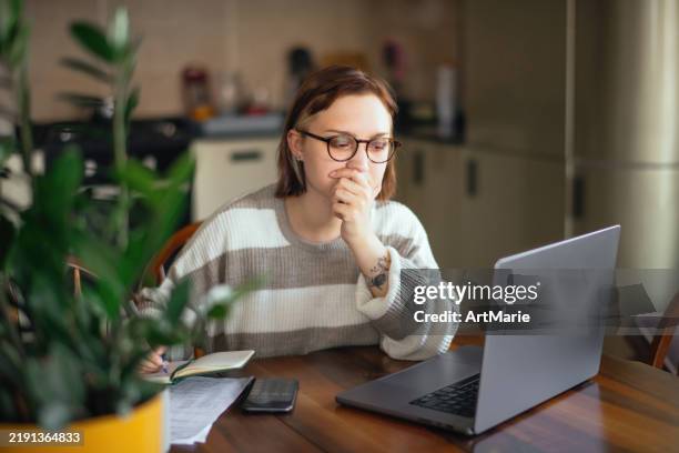 junge frau mit laptop, die zu hause bank- oder finanzpapiere/kontoauszüge überprüft - wirtschaftskriminalität stock-fotos und bilder