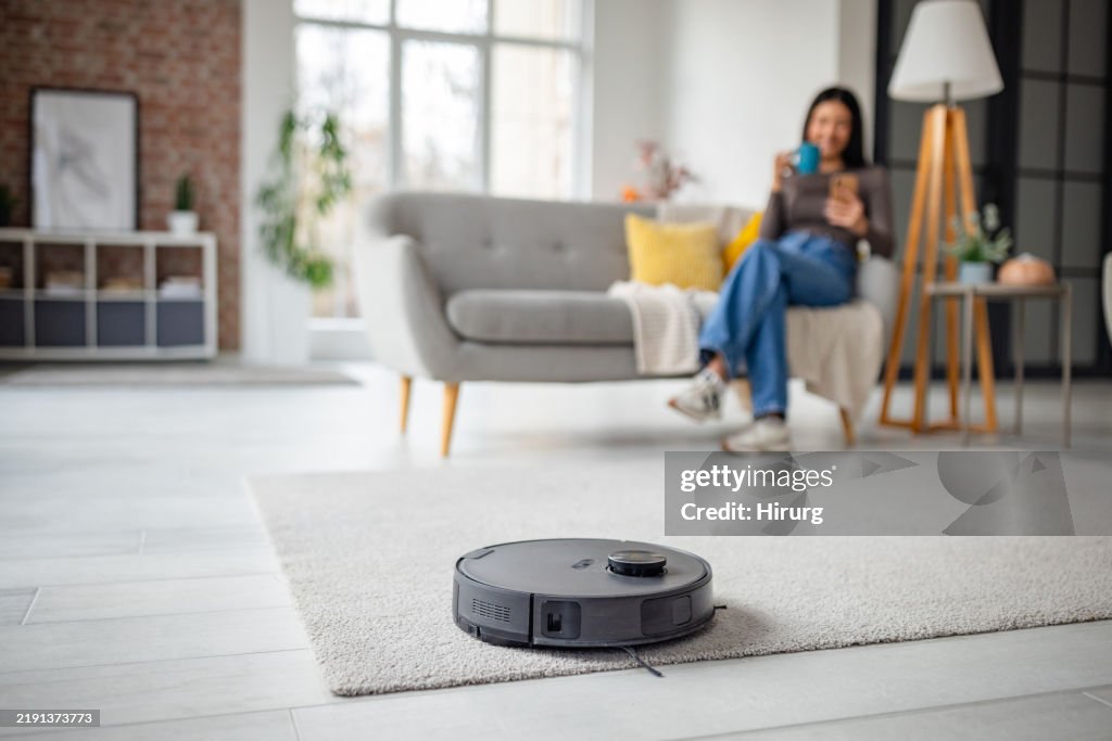 Frau entspannt sich mit Kaffee, während Roboter den Raum staubsaugt