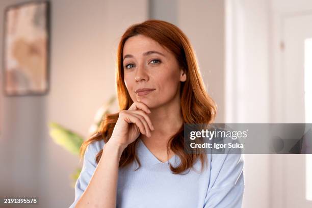 confident young woman in casual outfit posing thoughtfully indoors - sorriso discreto imagens e fotografias de stock