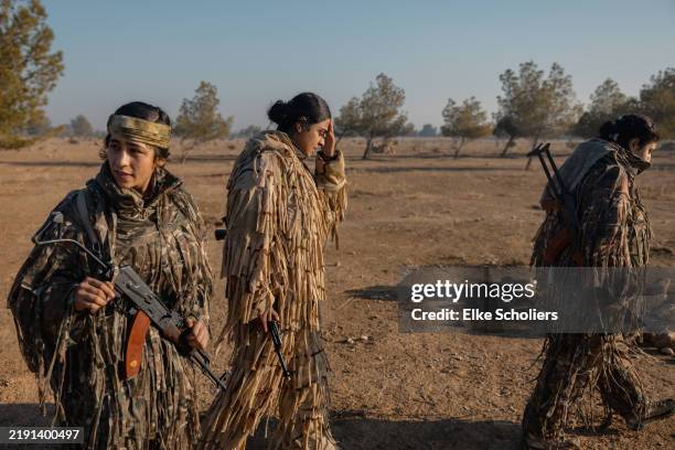 Fighters await their turn to shoot various guns in a remote training camp on December 25, 2024 in Al-Hasakah, Syria. Kurdish female fighters are...