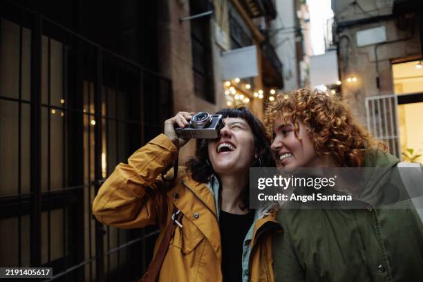 cheerful lesbian couple taking pictures in a city alley - divertimento imagens e fotografias de stock