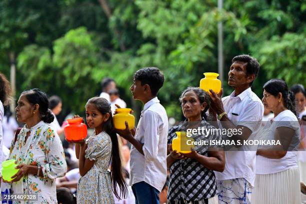 Devotees hold water pots before offering prayers during New Year's Day at Kelaniya Buddhist temple in Kelaniya on January 1, 2025.