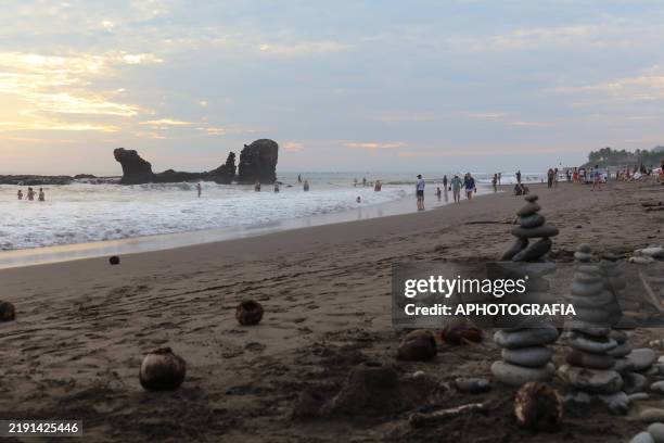People enjoying the waves of the sea during the last sunset at El Tunco beach on December 31, 2024 in La Libertad, El Salvador.