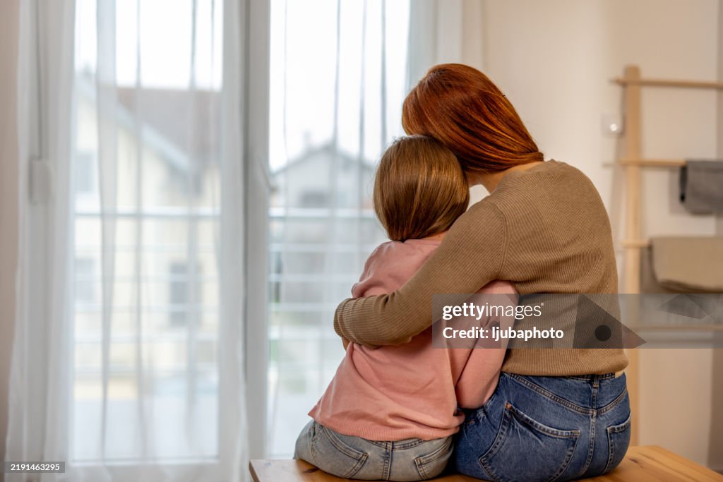 Mother Comforting Daughter by Embracing Her in a Home Setting