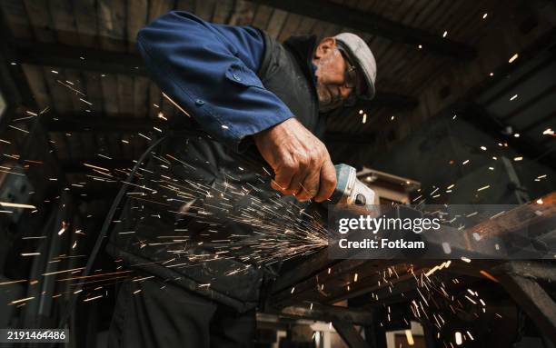 an older man, grinding in his workshop. - slijptol stockfoto's en -beelden