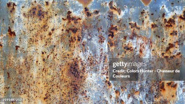 close-up of a rusty and weathered metal plate in shades of yellow, brown, gray and blue in paris, france. rough texture. sunlight. colors. - rouillé photos et images de collection