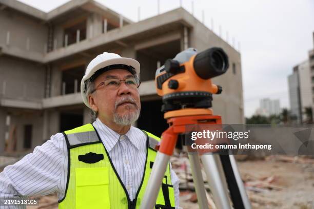 a senior construction male engineer working with the theodolite camera at the housing under construction - tacheometer stock pictures, royalty-free photos & images