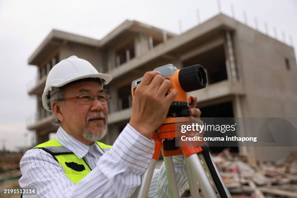 ein leitender bauingenieur arbeitet mit der theodolit-kamera am zu bauenden gehäuse - stativ stock-fotos und bilder