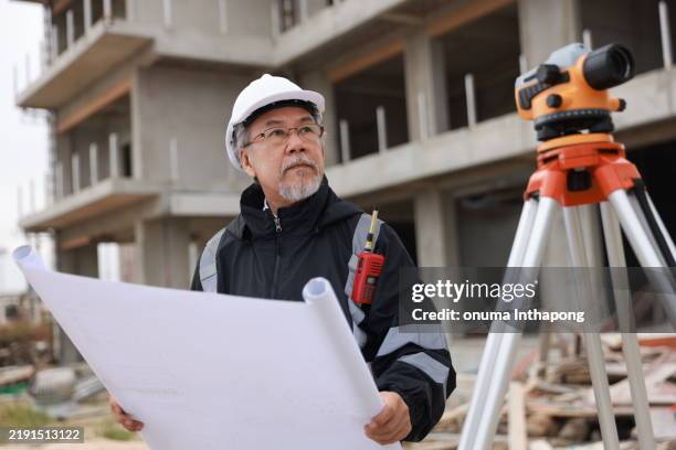 senior engineer with black safety jacket works with drawing and surveying level camera, construction site - tacheometer stock pictures, royalty-free photos & images