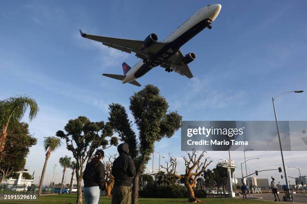 People watch a Delta Airlines plane landing from a park next to Los Angeles International Airport following the Christmas holiday on December 26,...
