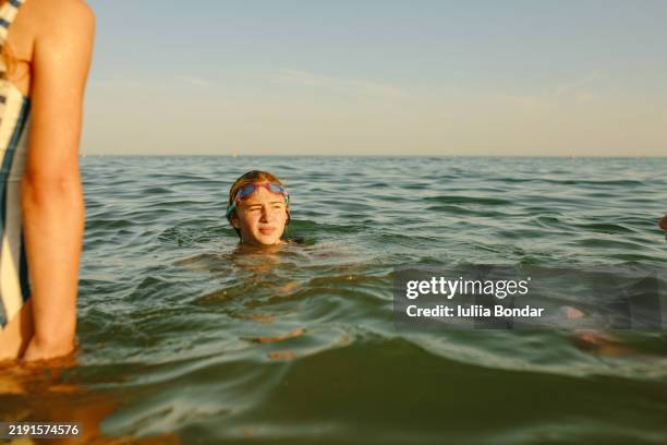 a young girl enjoy swimming. serene swim under the evening sun - water surface stock pictures, royalty-free photos & images