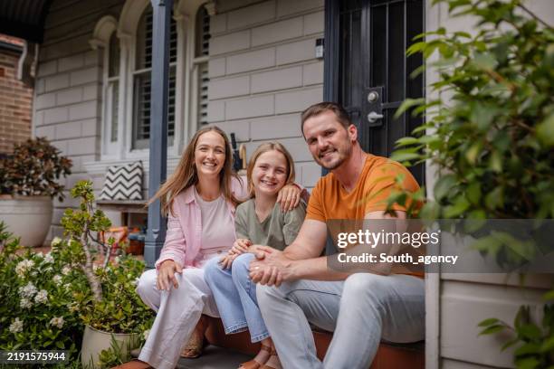 familia sonriente sentada antes de la entrada de su casa - cultura australiana fotografías e imágenes de stock