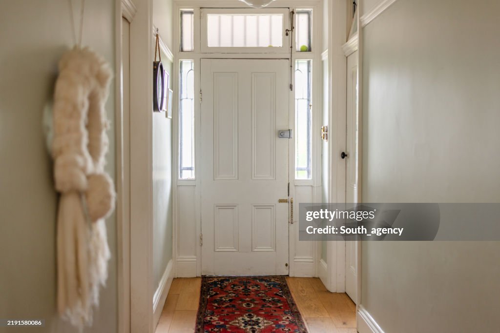 Narrow hallway with white door and decorative carpet