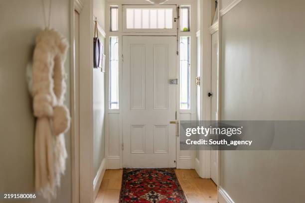 narrow hallway with white door and decorative carpet - simple living stock pictures, royalty-free photos & images