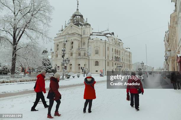 People walk past the snow-covered Slovak National Theatre as heavy snowfall covers Kosice, the second biggest city of Slovakia as a result of...