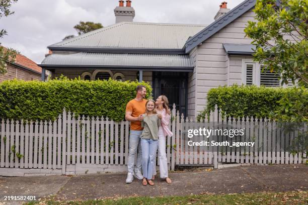 family in front of charming suburban house and fence - australian culture stock pictures, royalty-free photos & images