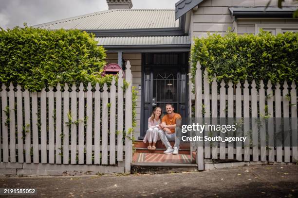 couple sitting on steps of charming suburban home - australia stock pictures, royalty-free photos & images