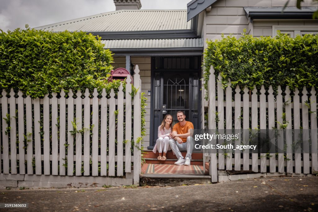 Couple sitting on steps of charming suburban home