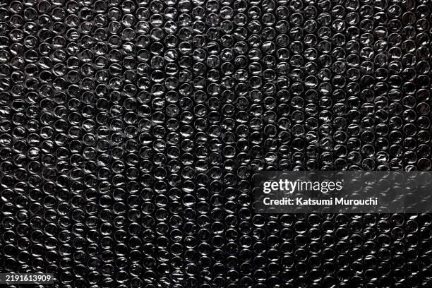bubble pack on black background - luftpolsterfolie stock-fotos und bilder