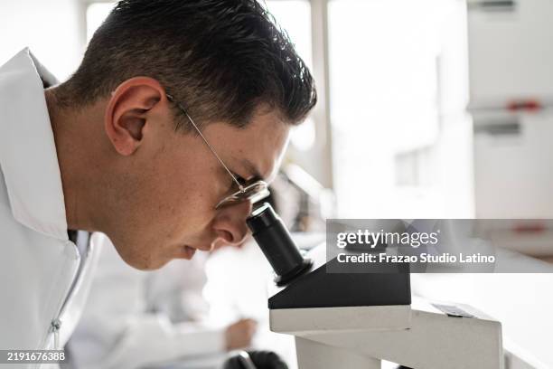 scientist man using a microscope on a laboratory - pathologist stock pictures, royalty-free photos & images