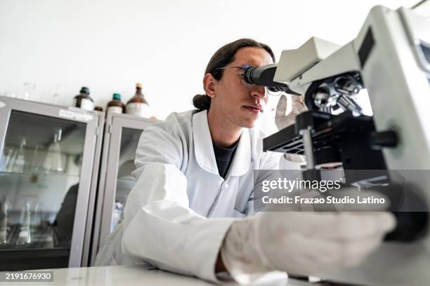 scientist man using a microscope on a laboratory - pathologist stock pictures, royalty-free photos & images