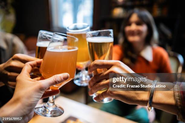 primer plano de amigos brindando con cerveza en un bar - cerveza-tipo-ale fotografías e imágenes de stock
