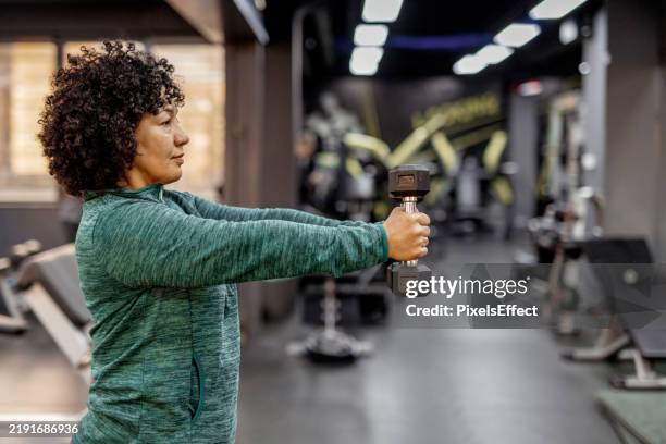 determined woman building strength with dumbbell exercises - strength training stock pictures, royalty-free photos & images