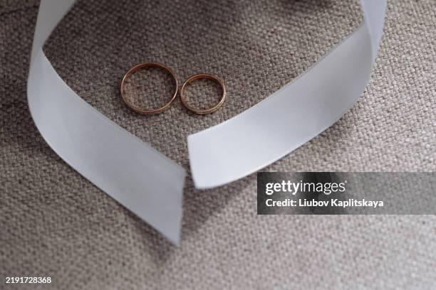 two wedding rings and white ribbon on gray fabric background. - gold heart frame stock pictures, royalty-free photos & images