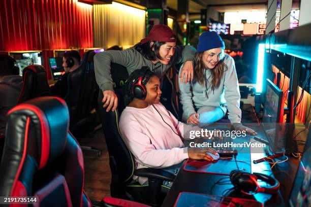 groupe multiethnique de jeunes amis jouant à des jeux vidéo - bâtiment public photos et images de collection