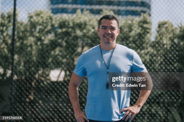 australian multiracial male coach looking at camera smiling standing in front of sport court - male likeness stock pictures, royalty-free photos & images