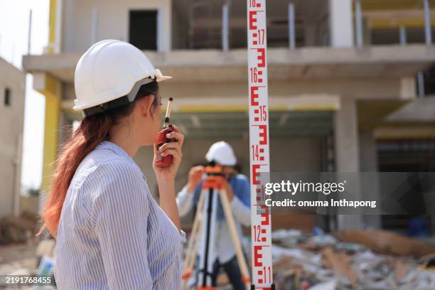 two survey engineers team working with surveying level cameras and transition level at the home office construction site - tacheometer stock pictures, royalty-free photos & images