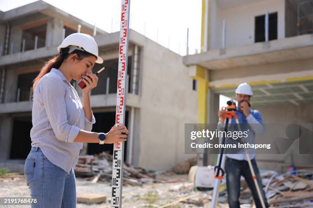 two survey engineers team working with surveying level cameras and transition level at the home office construction site - tacheometer stock pictures, royalty-free photos & images