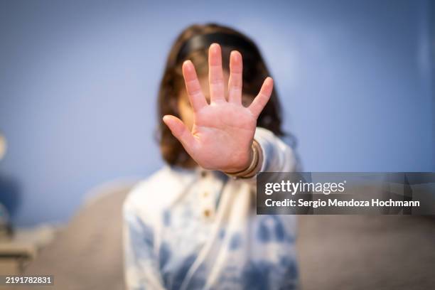 young pre-teen girl gesturing to stop, hand obscuring her face - abuso di minore foto e immagini stock