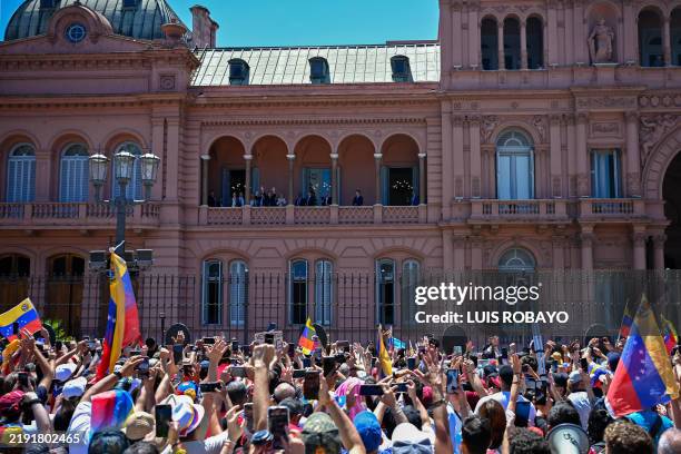 Venezuelan opposition leader Edmundo Gonzalez Urrutia waves to supporters gathering in Plaza de Mayo next to Argentina's President Javier Milei, at...