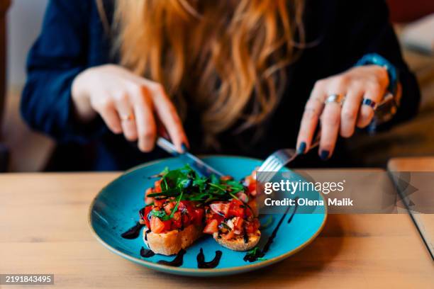 woman eating bruschetta with fresh tomato and arugula - roquette photos et images de collection