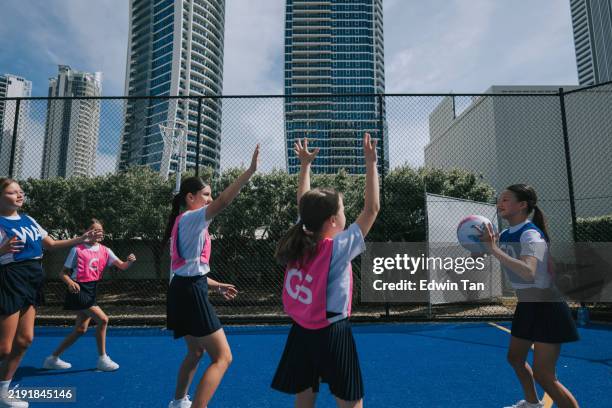 young australian netball team player trying to pass netball to her teammate in netball competition match - netball stock pictures, royalty-free photos & images