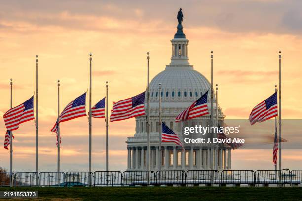 Flags on the National Mall fly at half-staff at daybreak with the U.S. Capitol in the background in honor of the passing of former U.S. President...