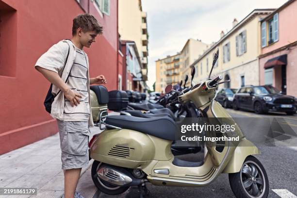 adolescente che ammira gli scooter a motore parcheggiati sul lato della strada a nizza, in francia. - motorino foto e immagini stock