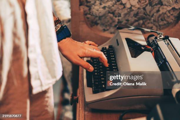 woman using a retro typewriter in a cozy vintage setting - drehbuchautor stock-fotos und bilder