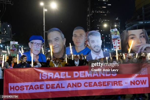 Protesters hold photos of hostages held in the Gaza Strip and 100 light sticks to symbolize 100 hostages held by Hamas during a rally calling for a...