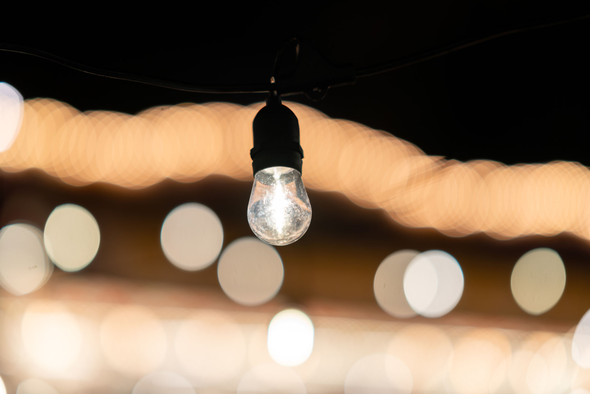 Single light bulb hanging, creating a warm and inviting ambiance in the dark Single light bulb hanging, creating a warm and inviting ambiance in the dark